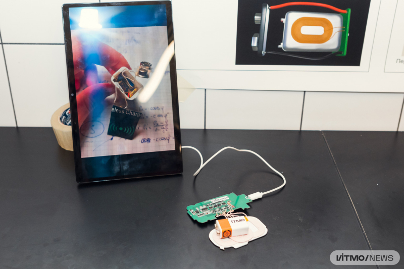 The prototype of the new device placed on a Qi-certified wireless charger. The white platform is a transmitter and the chip board is its power source. Photo by Dmitry Grigoryev / ITMO.NEWS
