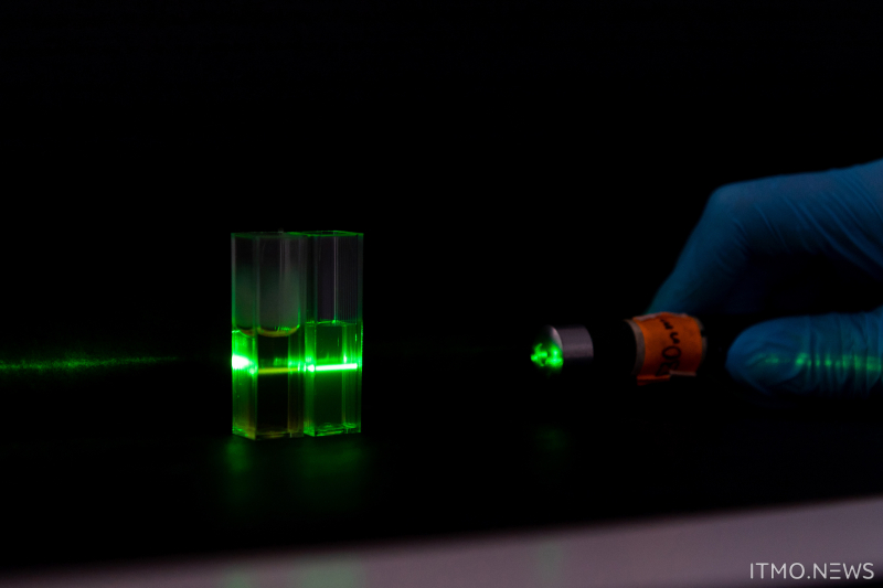 Кювета с углеродными точками на поверхности нанокристаллической целлюлозы в растворе диметилсульфоксида и воды (слева) и кювета с этим же образцом в растворе воды (справа). При дневном свете две жидкости будут желтого цвета, но при зеленой подсветке первая кювета станет оранжевой, а вторая - зеленой. Фото: Дмитрий Григорьев / ITMO.NEWS
